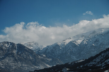 Panoramic view of snow-capped mountains against a blue cloudy sky.