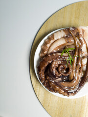 Fresh octopus on a white plate ready for cooking. Seafood on white background