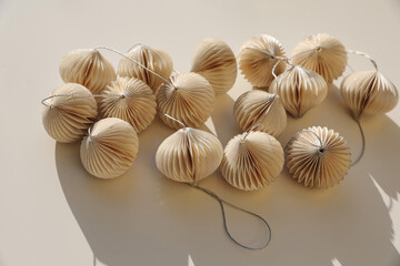 Elegant Christmas ornaments decor. Glittering white paper Christmas balls, baubles isolated on beige table background. Festive winter banner. Flat lay, top view. No people, copy space. Selective focus