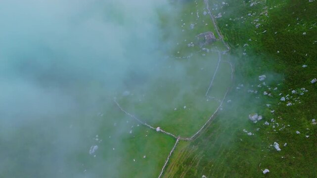 Fog in the spring landscape of pastures and Pasiegas cabins in the Natural Park of the Collados del As&oacute;n. Aerial view from a drone. Hills of Ason Natural Park. Soba Valley, Cantabria, Spain, Europe