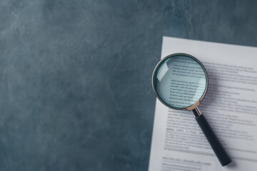 Magnifying glass placed over documents on a textured surface signifying detail-oriented analysis, research, and investigation.