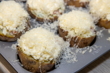 A selection of delicious uncooked Fish Pie Potato Skins topped with cheese and garnish ready to be put in the oven
