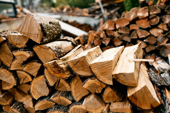 large stack of firewood with axe resting on top in rustic outdoor setting