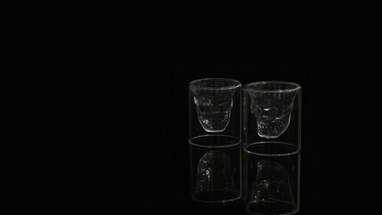 A pair of skull shaped shot glass on a black background