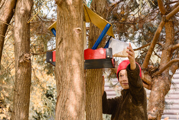 Little boy feeding birds filling DIY birdfeeder in backyard on Fall day
