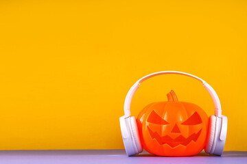 Halloween music, playlist for Halloween party holiday concept background. Pumpkin Jack Lantern in big white headphones, on bright background, copy space
