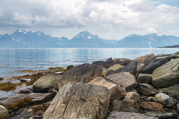 Steine am Ufer des Lyngenfjord mit Blick auf die Berge der Lyngenalpen
