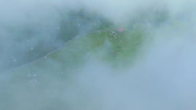 Fog in the spring landscape of pastures and Pasiegas cabins in the Natural Park of the Collados del As&oacute;n. Aerial view from a drone. Hills of Ason Natural Park. Soba Valley, Cantabria, Spain, Europe