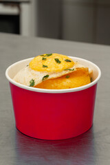 Delicious couscous with fried egg in a red bucket.