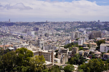 Obraz premium The densely packed skyscrapers of the city of Algiers reach far into the distance, as far as the eye can see, with the Monument to Martyrs on the horizon at the left.