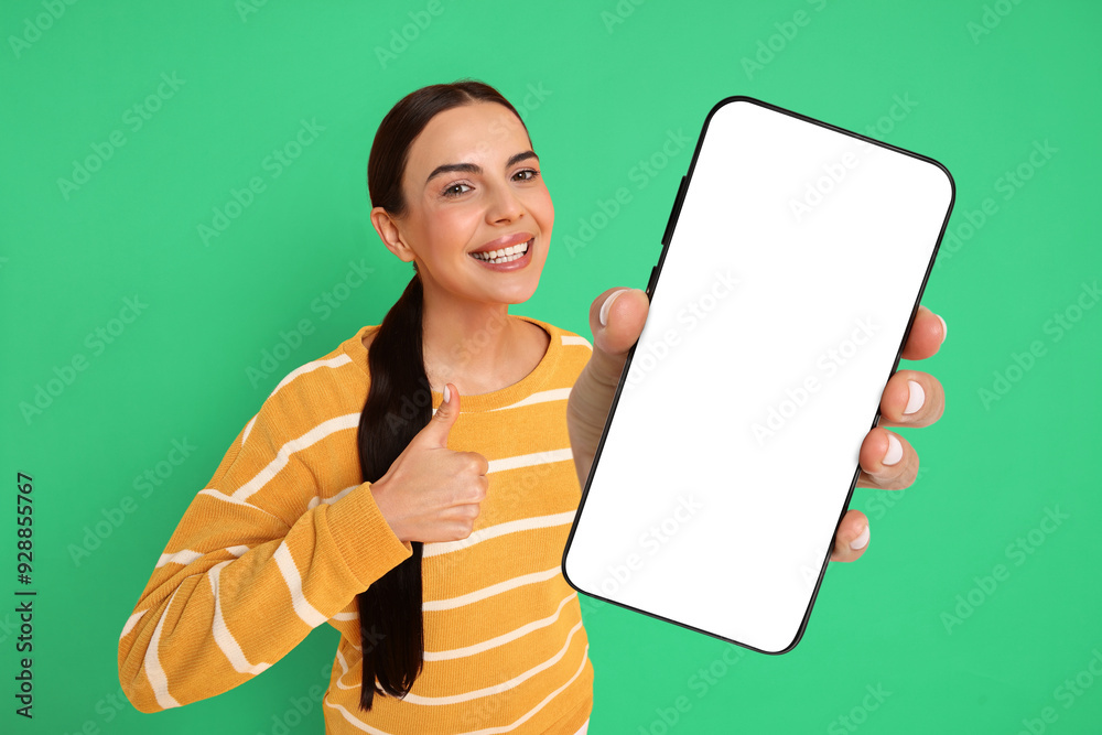 Wall mural Happy woman showing mobile phone with blank screen on green background. Mockup for design