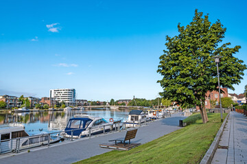 Uferpromenade und Hafen der Stadt Leer am Morgen. Im Hintergrund sind einige Gebäude zu sehen