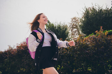 Photo of attractive excited girl dressed bomber short skirt backpack enjoying wind blowing walking...