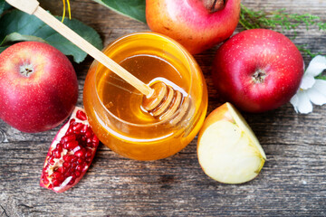 rosh hashana holiday - honey jar with apples and pomergranates on rustic background, top view