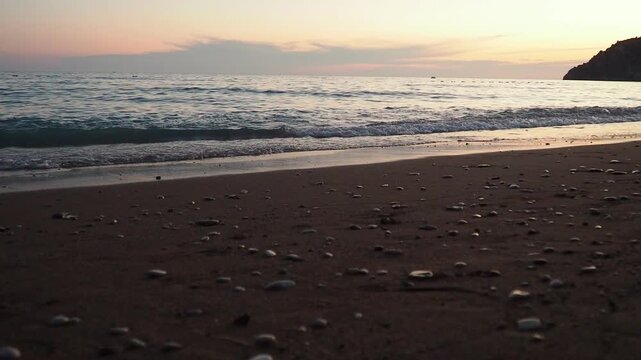 Waves gently lap at shore during stunning sunset over ocean. Golden sunlight reflects off waves as they roll onto shore, creating tranquil atmosphere at sunset by sea. Montenegro summer Canj