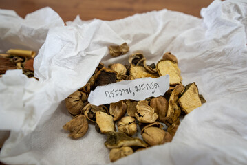 Asian traditional herbs and spices, dried and prepared, shown on a wooden table, on tissue or in cups.
