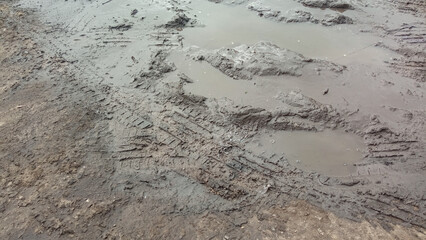 The rain washed out the highway. Potholes on the road. Dirt and people on the road. Traces of car wheels on the road. Impassability of roads.