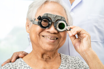 Asian senior woman wearing ophthalmic vision eye test and using optical trial frame.