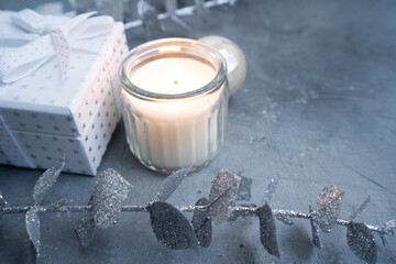 A serene holiday setup features a candle, elegant soap, and chic silver foliage on a textured background
