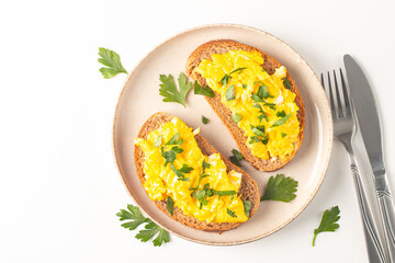 Scrambled eggs with green herbs on wheat-rye crispy toast.