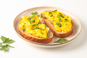 Scrambled eggs with green herbs on wheat-rye crispy toast.