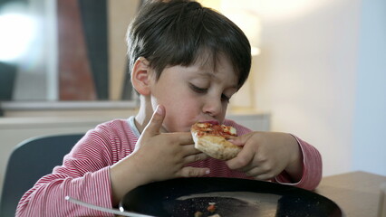 Child enjoying a slice of pizza at the dining table, capturing the joy and innocence of childhood...