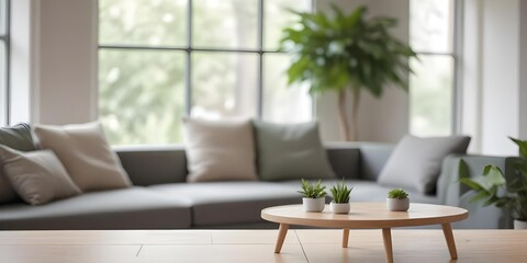 A wooden table is in the foreground with a blurred gray sofa and green plants in the background.