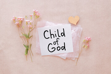 I am a child of God - christian text on card with little flowers and heart on light pink background, biblical verse and religion concept