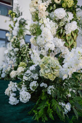 Decor details closeup. Location for luxury wedding ceremony. Arch decorated white flowers, greens, greenery. Trendy decor in backyard. Celebration baptism concept. Birthday party reception.