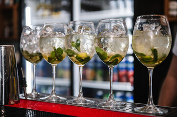 Closeup of Mojito cocktail on a bar counter. Five Mojito cocktails with mint leaves, and lime in restaurant.