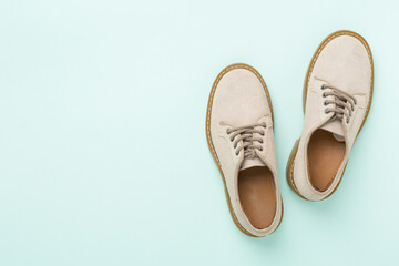 Beige suede shoes on color background, top view