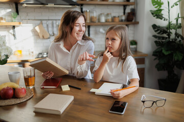 Pensive child doing homework near mother with book at home