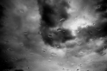 Cloudy sky seen from car window with rain drops on it. Black and white