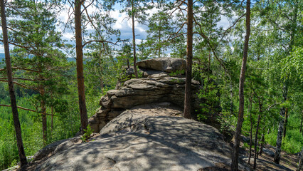Small Devils rock, Devil's Hillfort complex on sunny summer day. Iset Park, Iset village, Sverdlovsk region, Russia. Hiking. Pine trees on rock