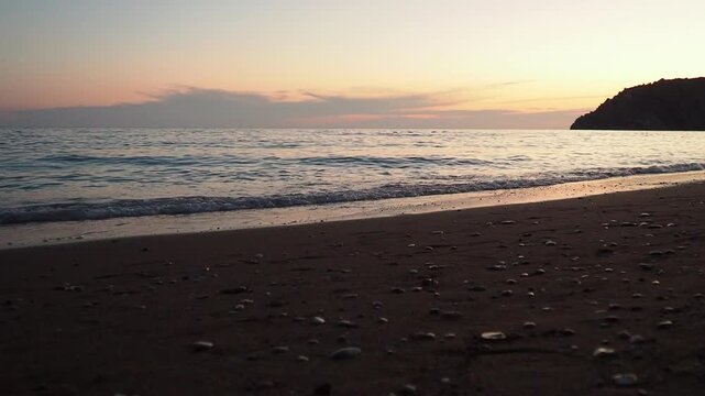 Waves gently lap at shore during stunning sunset over ocean. Golden sunlight reflects off waves as they roll onto shore, creating tranquil atmosphere at sunset by sea. Montenegro summer Canj