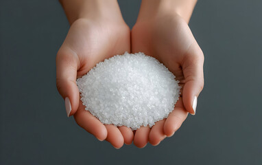 Hands holding a mound of salt, showcasing its purity and texture against a soft background.
