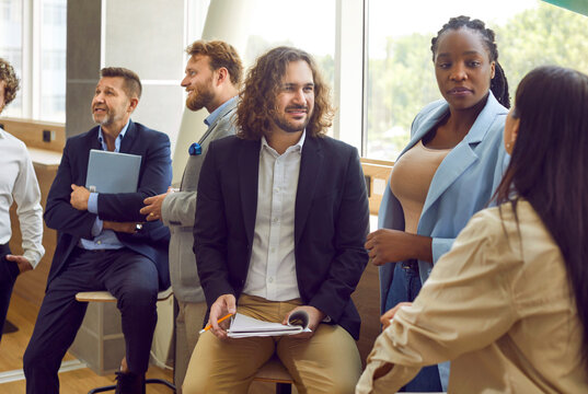 Diverse business professionals communicating at a conference, seminar or other educational event. Young and mature multiethnic people meeting in the office and having discussions. Banner background
