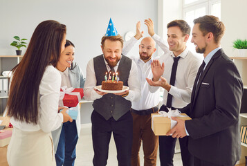 Office funny party, celebrating employee birthday with candle cake, happy coworkers friends. Group of workers gathering for special enjoyable event, birthday or anniversary, friendly company tradition