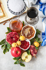 Jewish holiday Rosh Hashana festive table setting with plate, honey, apple ,pomegranates, dates, book of hebrew prayers, kiddush cup