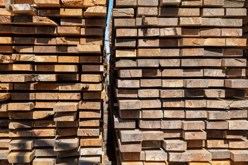 Fototapeta premium Stacked wooden planks close-up at lumber warehouse. Wood industry concept
