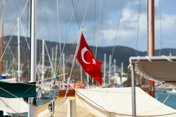 Vibrant Turkish flag stands out prominently on yacht in foreground, with soft-focus view of...