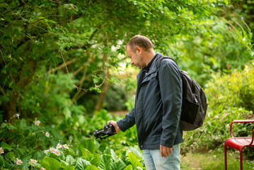 Obraz premium Man with Camera in Lush Garden Capturing Nature Photography