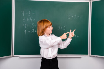 Photo of cute little schoolboy diligent point look empty space dressed stylish uniform classroom blackboard background
