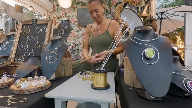4k Video at 25 fps of a Hispanic Jewelry Artisan Woman in Her 50s Handcrafting Earrings with Aluminum Wire at a Street Stall for Sale"