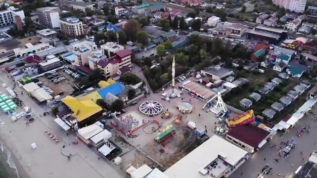 Aerial drone view from above of the center resort town with shops, restaurants and entertainment, hotels and an amusement park near sandy beach on Black sea in Zatoka resort, Odessa region, Ukraine
