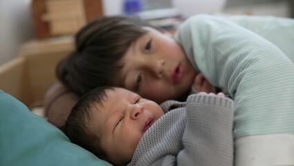 Older sibling and baby rest on a bed, sharing a peaceful and affectionate moment in a cozy room, highlighting the strong bond and love between them