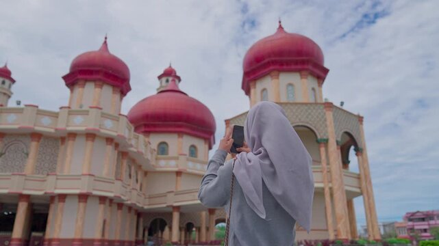 A woman photographs the beauty of the Baitul Makmur Grand Mosque in Indonesia