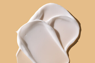 A smear of white cream on a beige background.