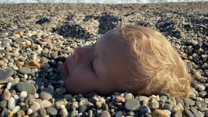 Children playing on the beach. Happy child face buried in sand close-up. Children summer vacation. Yevpatoriya, Crimea, Russia 2024