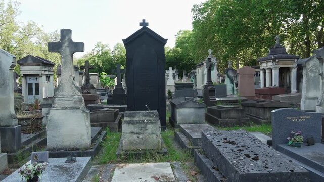 Ancient Parisian cemetery Montparnasse. Tombstones and crypts on graves. Old burial in the shade of trees. Memory of ancestors, peace of mind